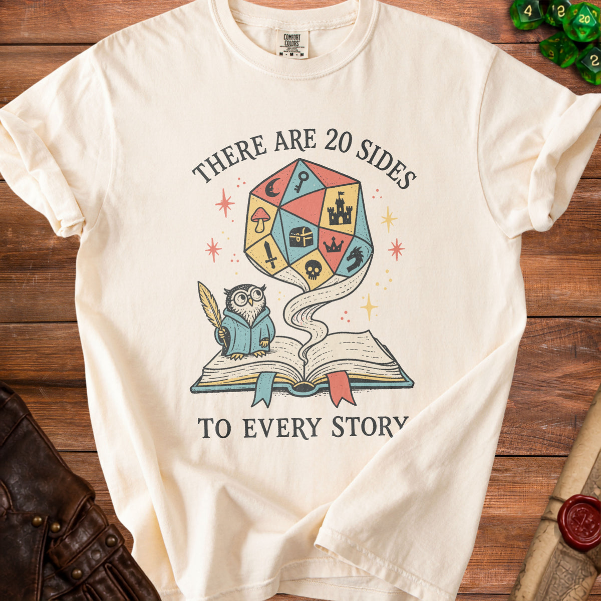 Cream t-shirt with graphic: owl, open book, and 20-sided die.