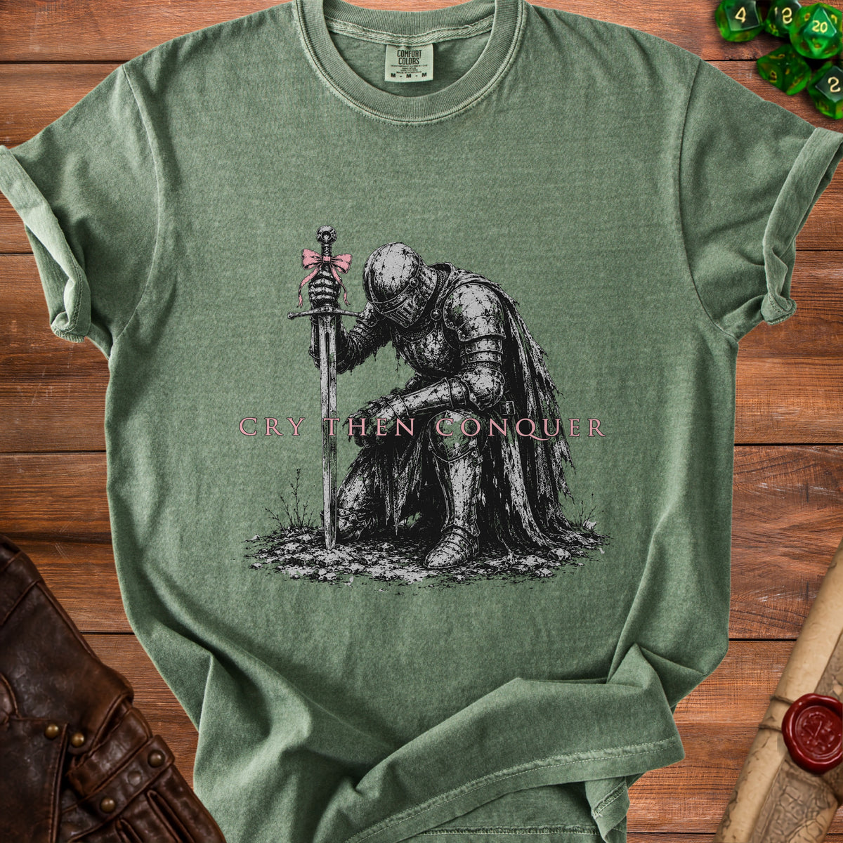 Green t-shirt with knight kneeling before sword and text "Cry Then Conquer".