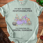 Light green t-shirt with a goblin character, books, pizza, and the text "I'm Not Avoiding Responsibilities I'm Curating My Mental Dungeon".