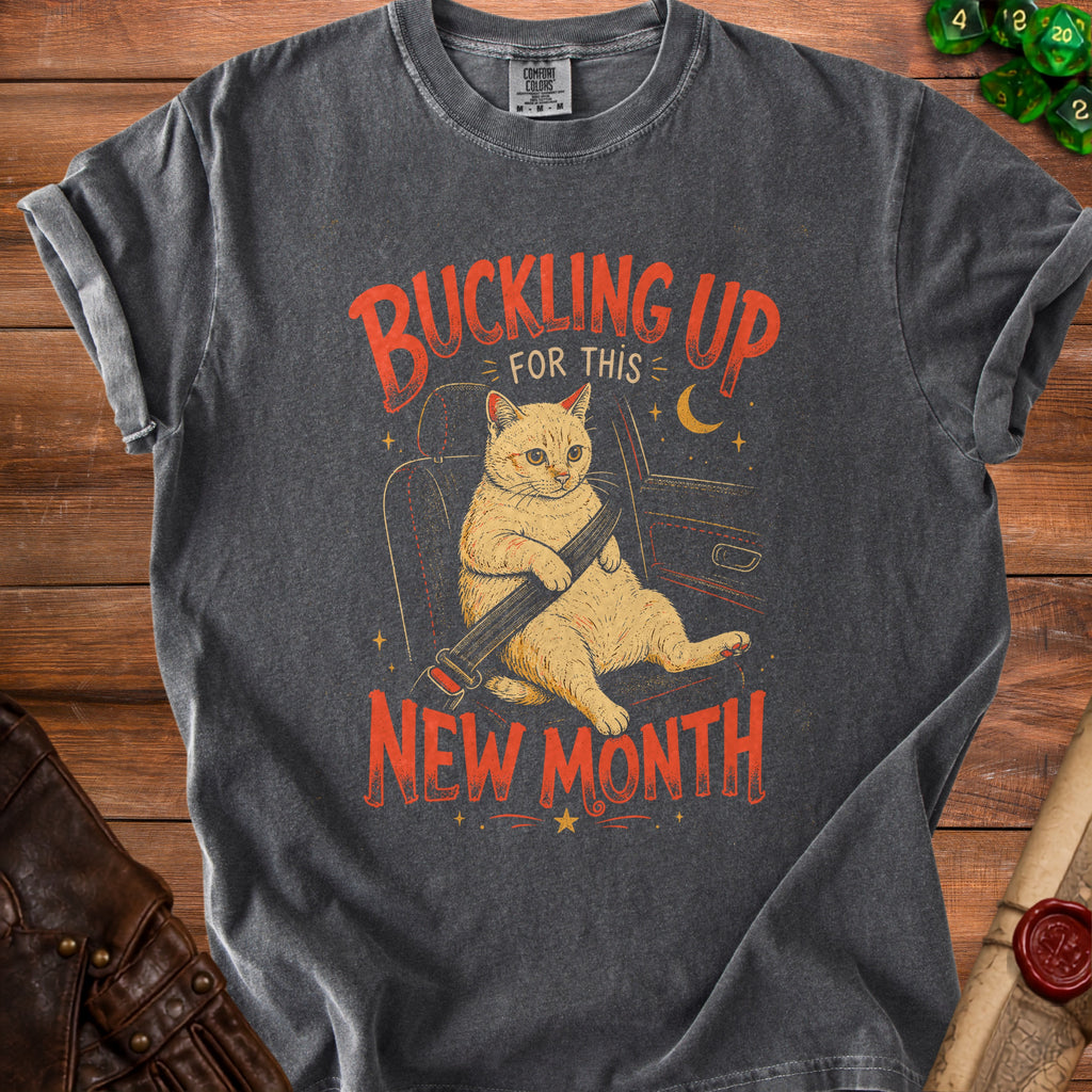 T-shirt with graphic of a cat in a car seatbelt, text "Buckling Up for this New Month".