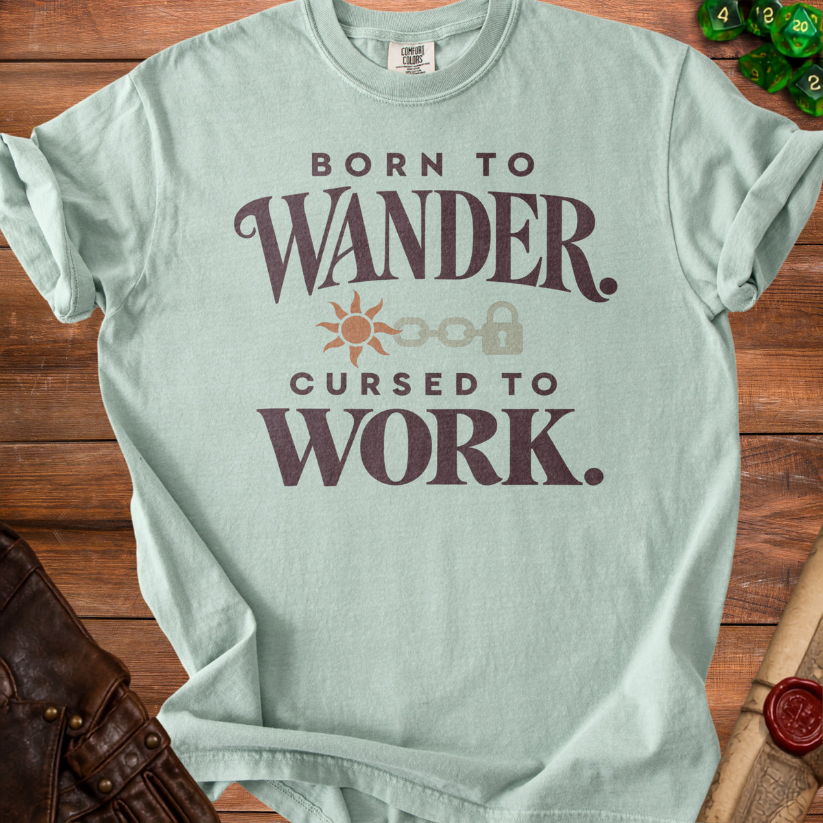 Light blue t-shirt with text "Born to Wander. Cursed to Work." and graphic.