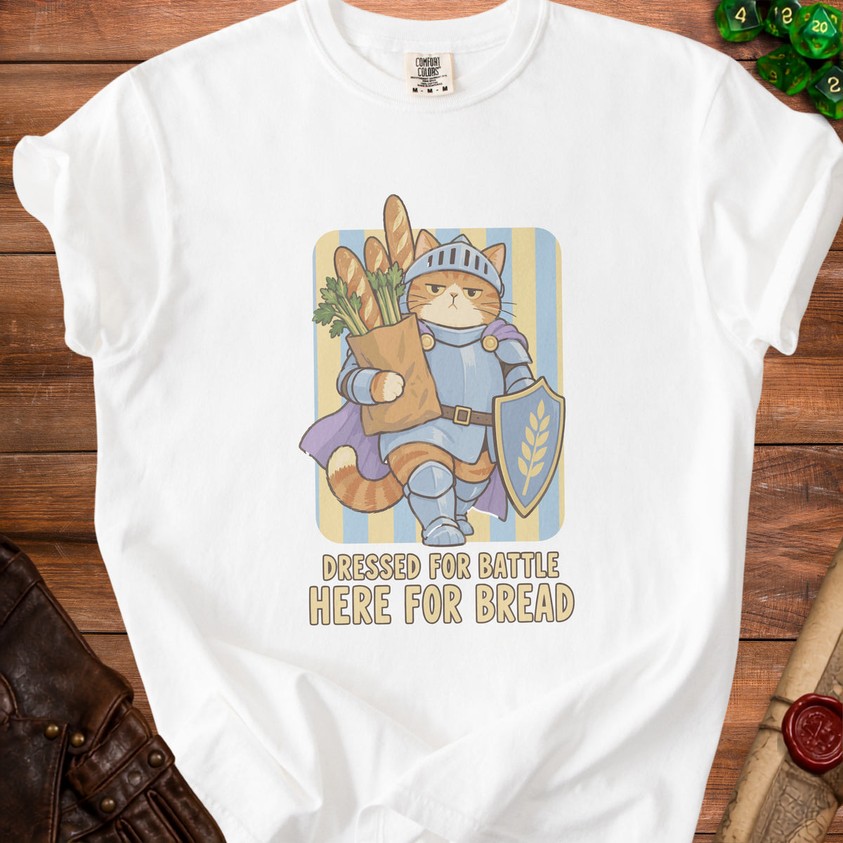 White t-shirt with graphic of knight cat holding baguettes and shield, text "DRESSED FOR BATTLE HERE FOR BREAD".