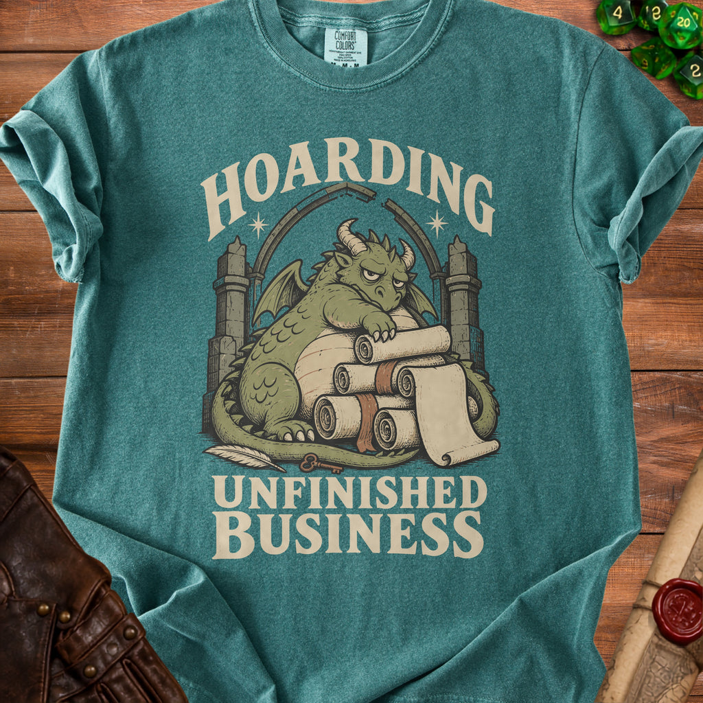 Teal t-shirt with a dragon hoarding scrolls and the text "HOARDING UNFINISHED BUSINESS".