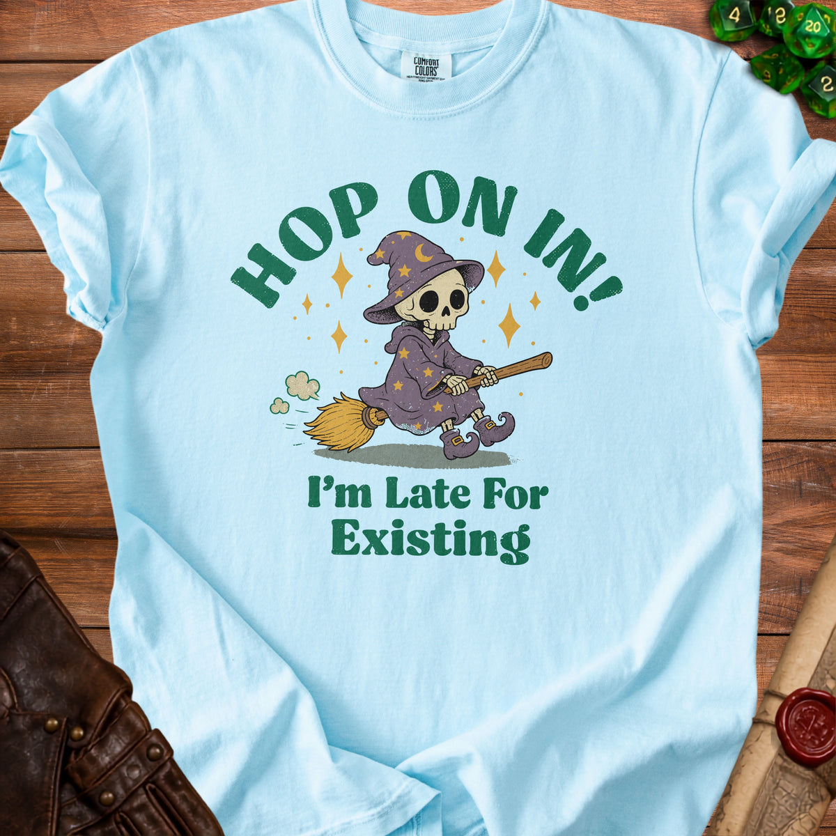 Light blue t-shirt with skeleton witch graphic and text "Hop On In! I'm Late For Existing".