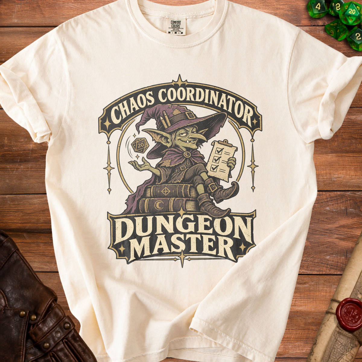 An off-white t-shirt featuring a fantasy graphic with a goblin wizard, a d20 die, and the text Chaos Coordinator Dungeon Master.
