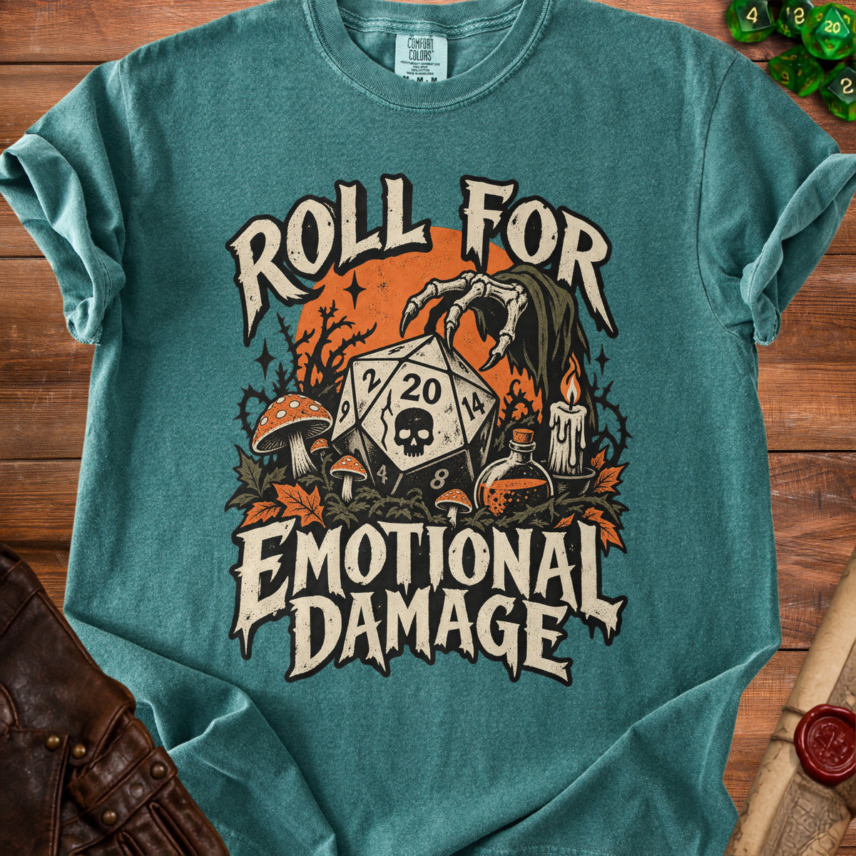Teal t-shirt with a D20 die, skeletal hand, mushrooms, and text "Roll For Emotional Damage".