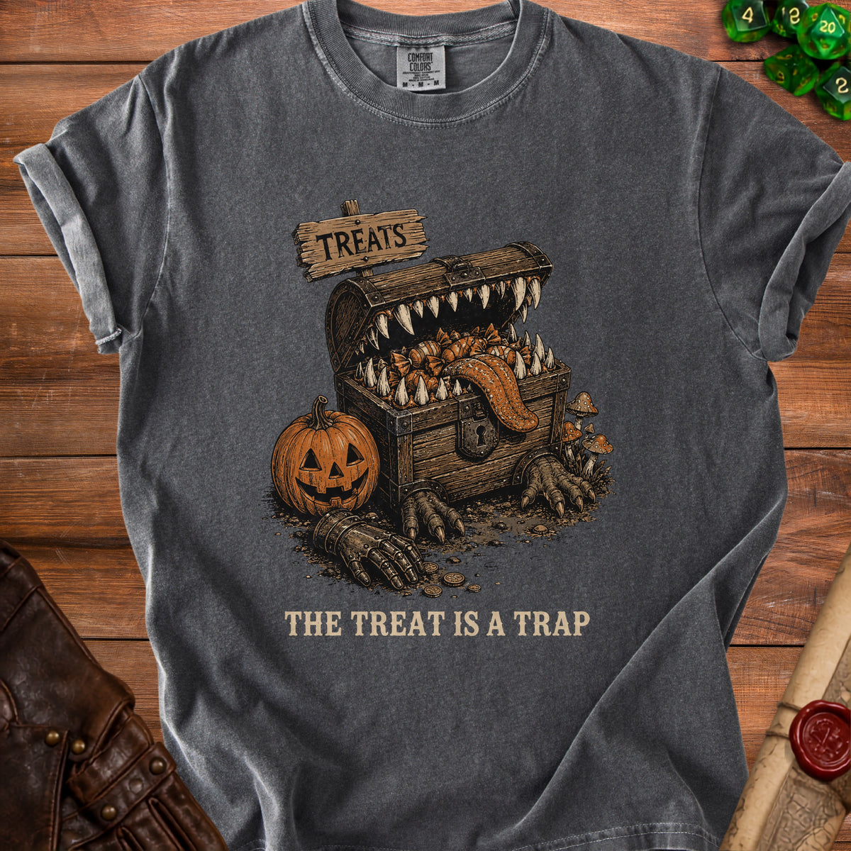 Dark t-shirt with a graphic of a monster chest, pumpkin, and text "The Treat Is A Trap".