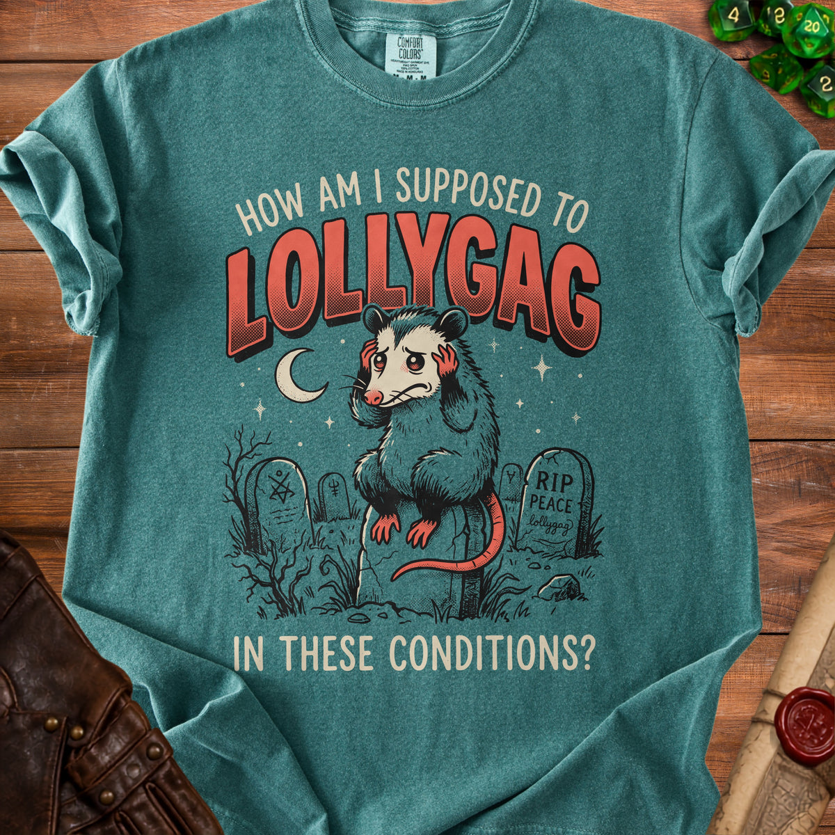 T-shirt with a graphic of a stressed possum sitting on a tombstone, reading "How Am I Supposed to Lollygag in These Conditions?"