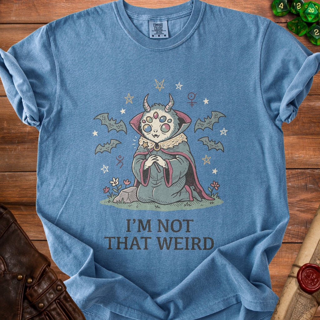 Blue t-shirt with cartoon creature, bats, stars, and text "I'M NOT THAT WEIRD".