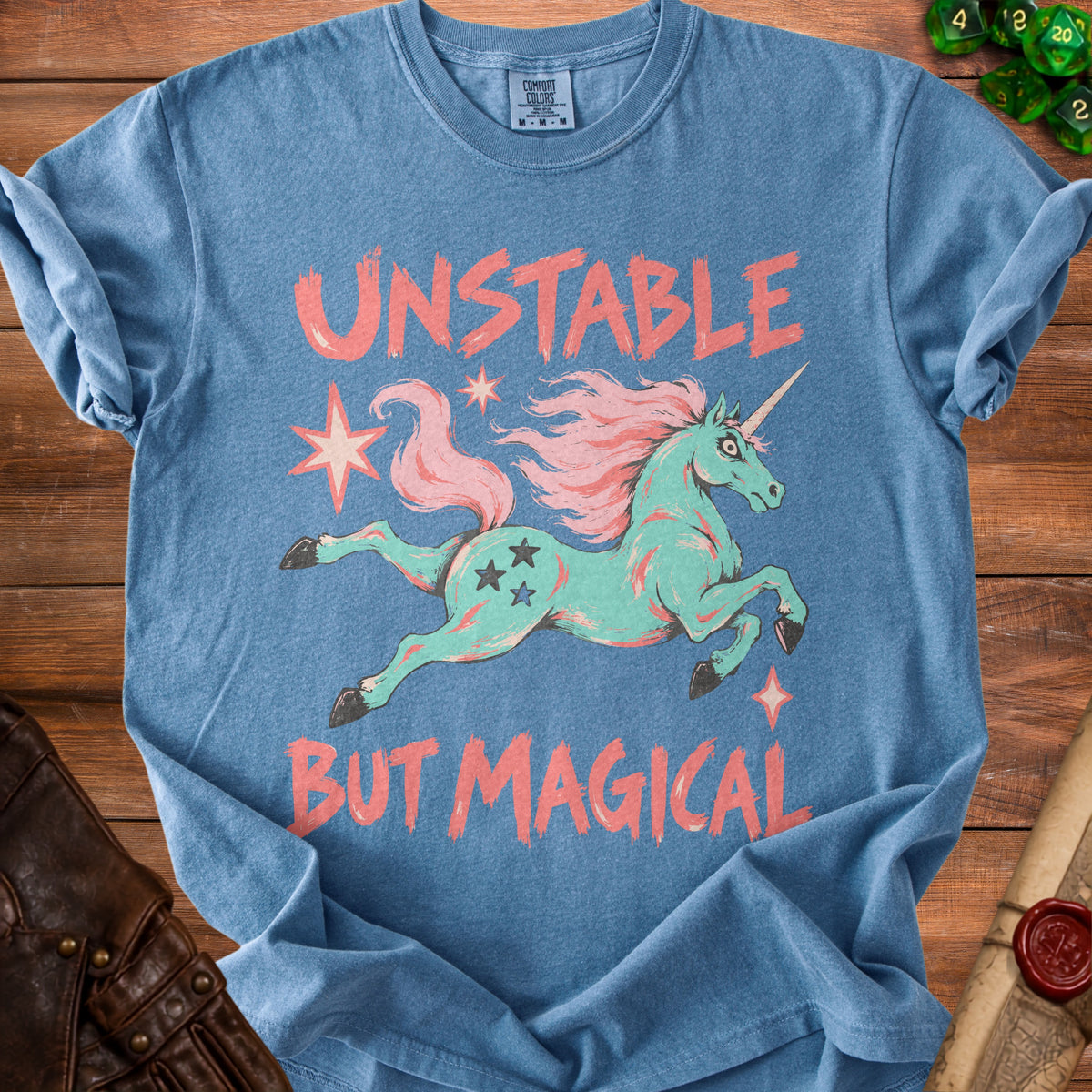 Blue t-shirt with text "UNSTABLE BUT MAGICAL" and a teal unicorn graphic.