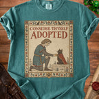 T-shirt with medieval-style art of a person in armor adopting a cat.
