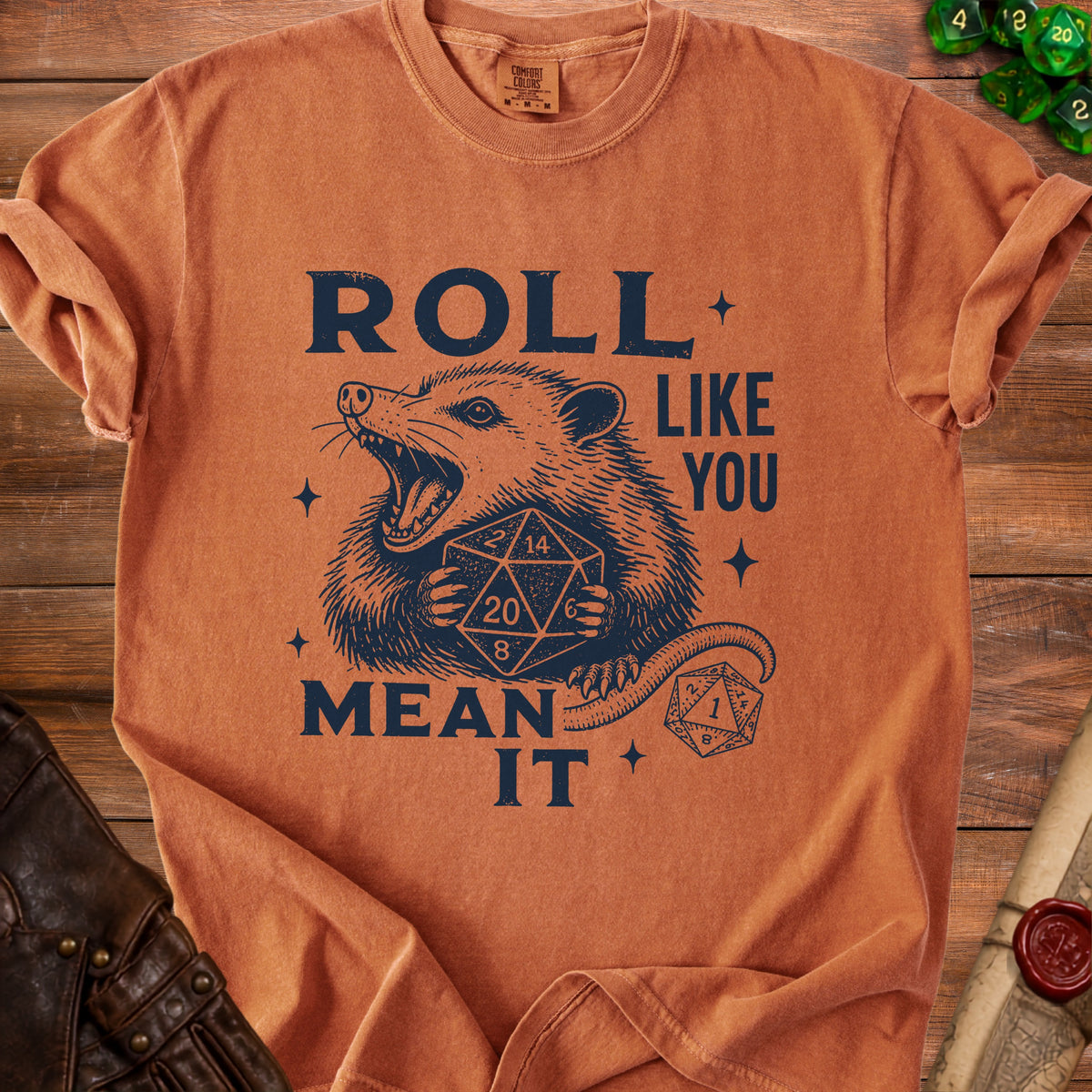 T-shirt with navy graphic of a possum holding dice, reading "ROLL LIKE YOU MEAN IT".