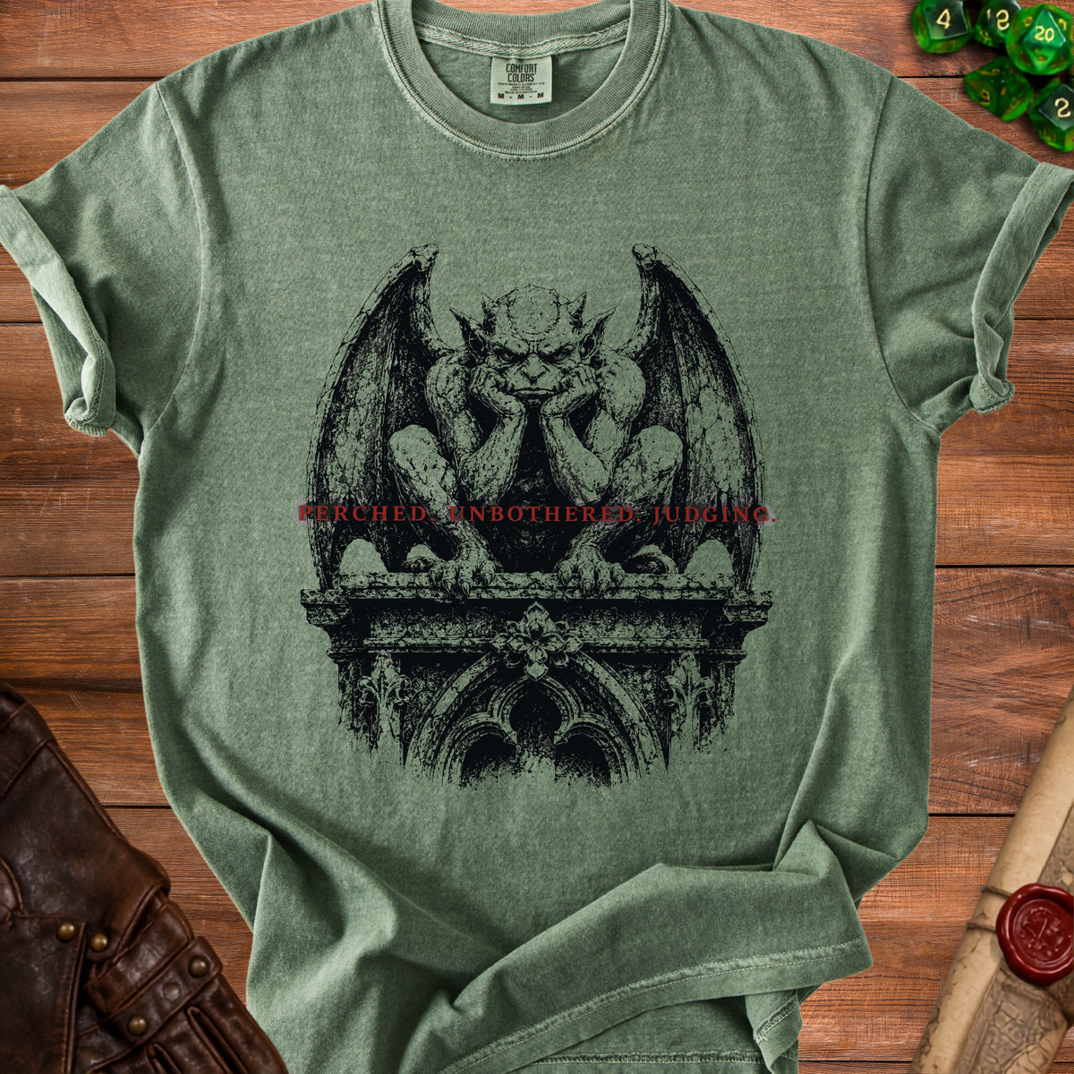 Green t-shirt with a black gargoyle graphic and red text reading "PERCHED UNBOTHERED JUDGING."