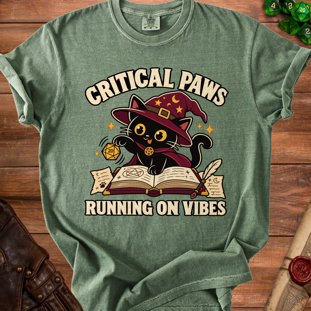 Green t-shirt with black cat wearing witch hat, reading book with text "CRITICAL PAWS RUNNING ON VIBES".