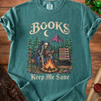 Skeleton reading by campfire with books, cat, and mountains, reads "Keep Me Sane".