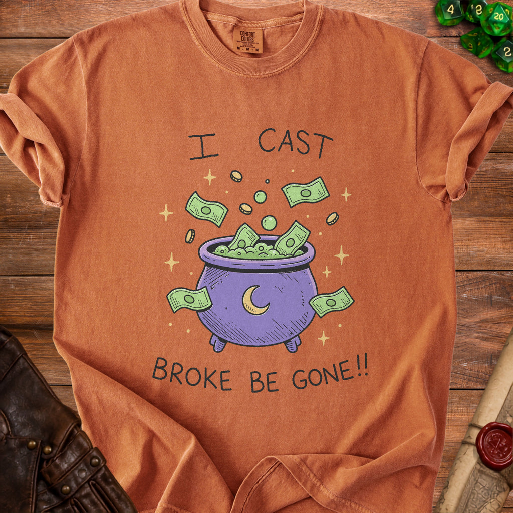 Orange t-shirt with a graphic of a cauldron overflowing with money and stars, saying "I CAST BROKE BE GONE!!".