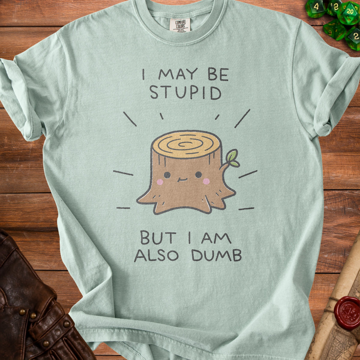 Mint green t-shirt with a cartoon stump and text "I MAY BE STUPID BUT I AM ALSO DUMB".