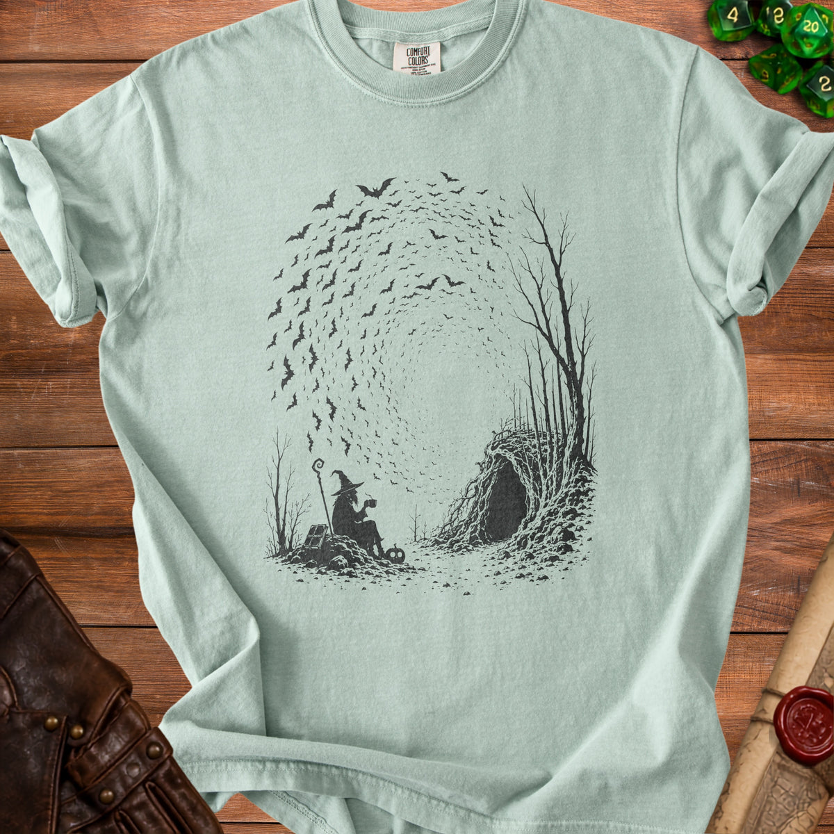 Witch with staff and pumpkin sits near cave entrance with bats swirling above.