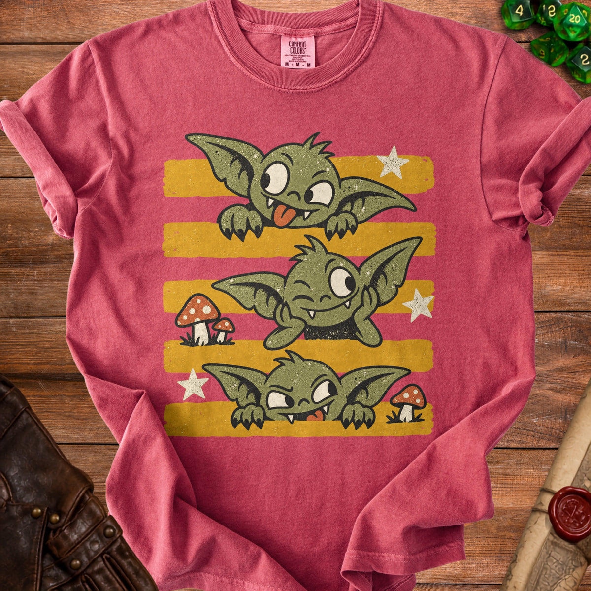 Red t-shirt with three green goblins with stripes, mushrooms, and stars.