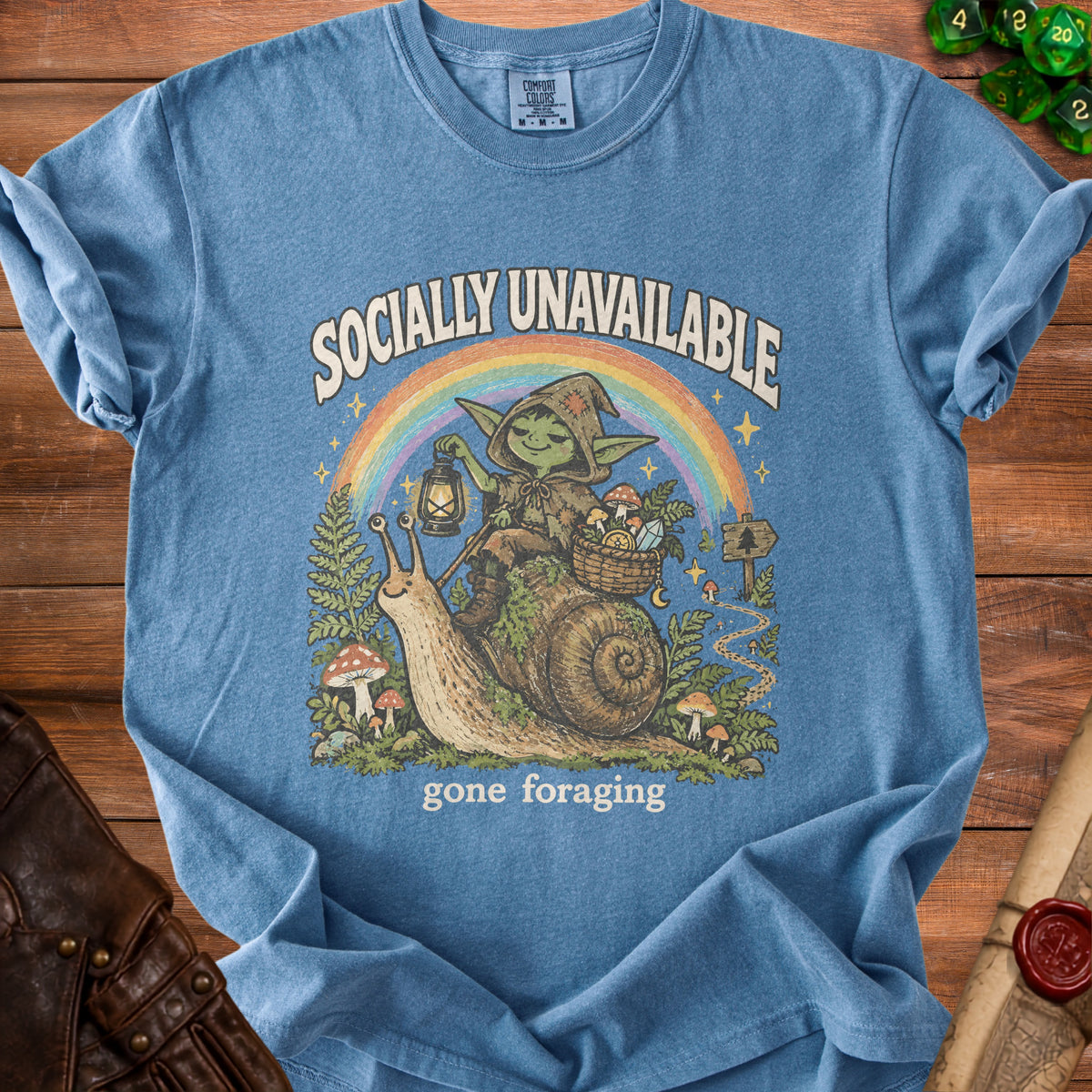 Blue t-shirt with illustration of a goblin on a snail, "Socially Unavailable gone foraging".