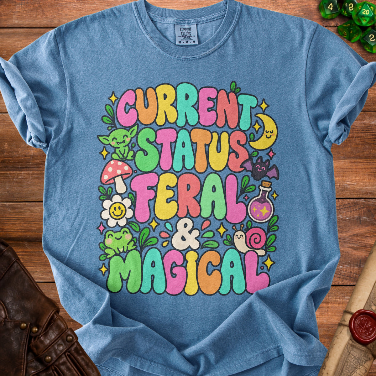 Blue t-shirt with "Current Status Feral & Magical" text and whimsical graphics.