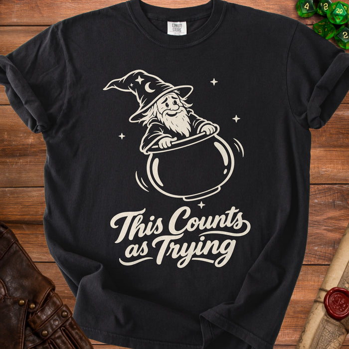 Black t-shirt with a cartoon wizard in a cauldron and text reading "This Counts as Trying".