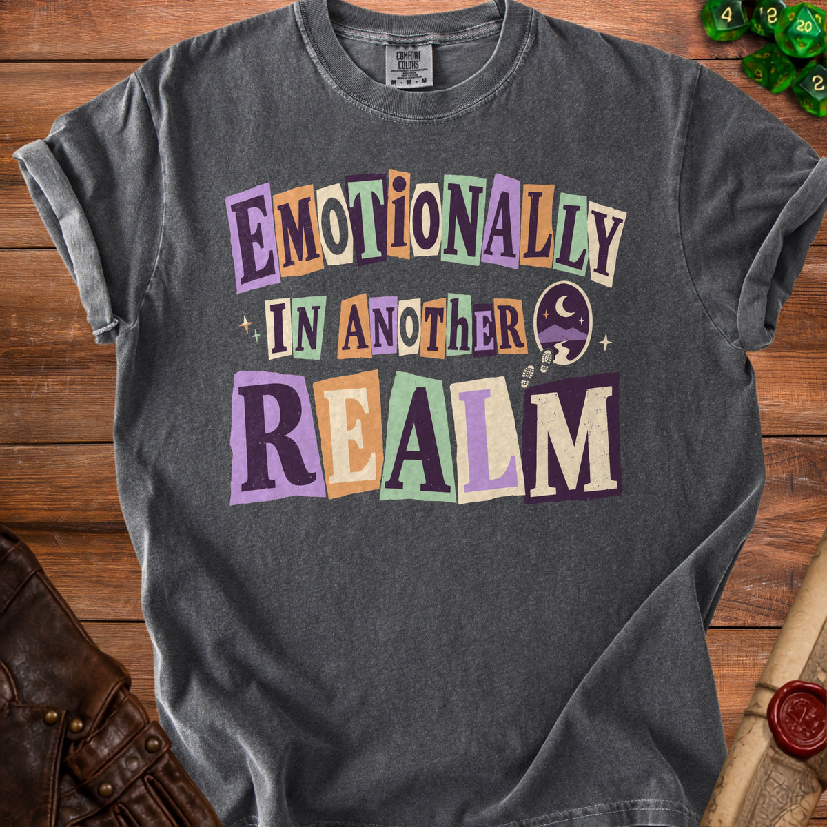 Comfort Colors charcoal t-shirt with "Emotionally In Another Realm" graphic and mountain scene.