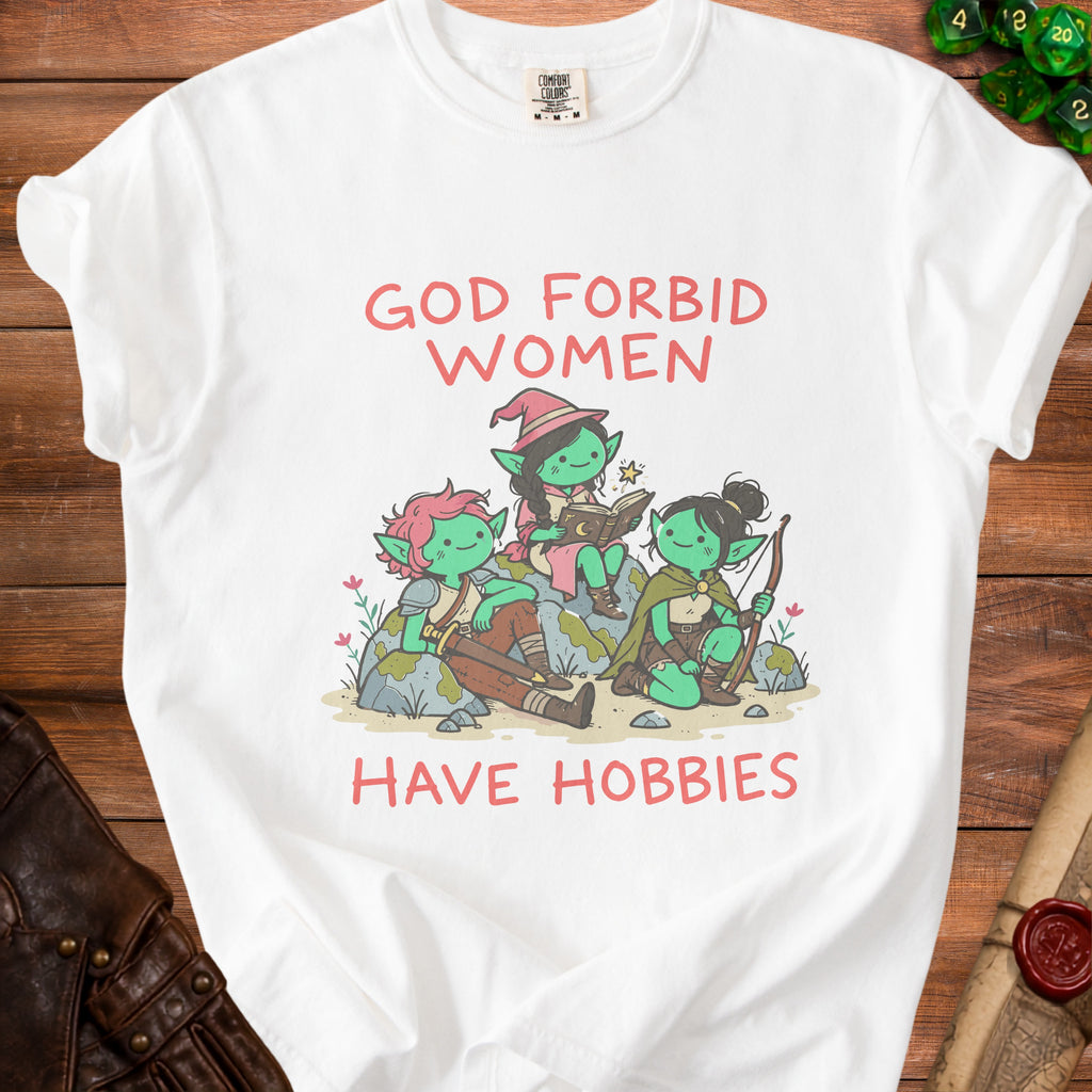 A white t-shirt featuring a graphic of three green female goblins and the text "God forbid women have hobbies."