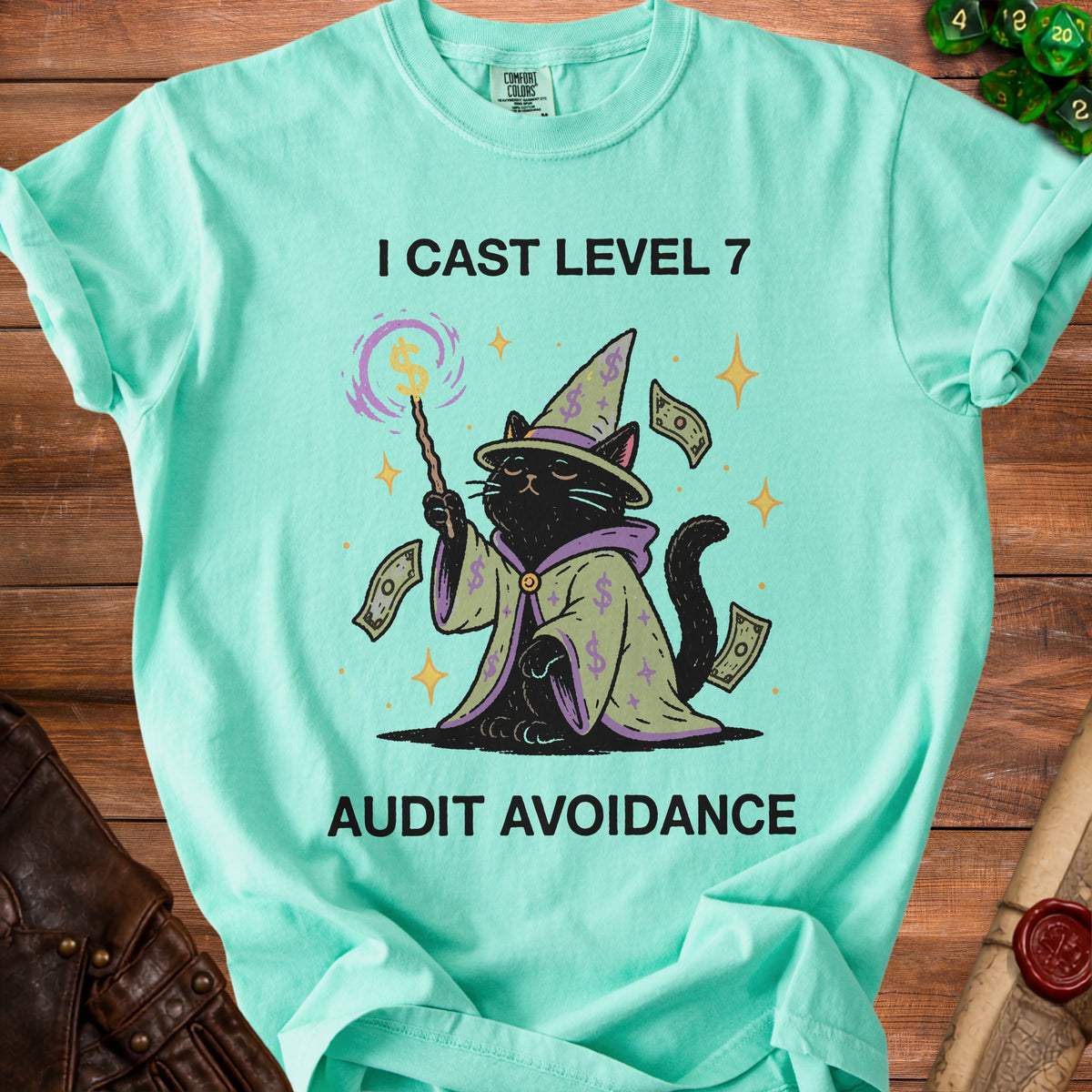 Mint t-shirt with black cat wizard casting money spells, text "I CAST LEVEL 7 AUDIT AVOIDANCE".