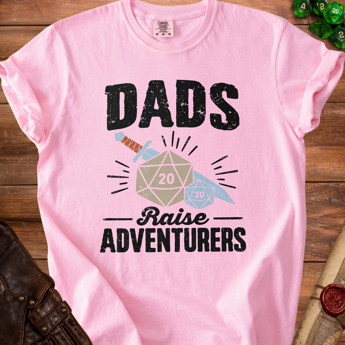 Pink t-shirt with black distressed text reading "DADS Raise ADVENTURERS" and graphics.