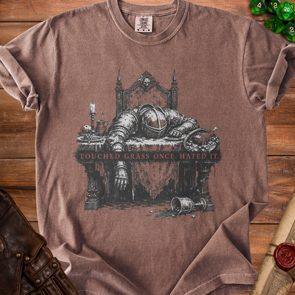 Brown t-shirt with graphic of knight sleeping at table, "TOUCHED GRASS ONCE. HATED IT."
