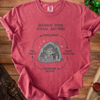 T-shirt with graphic "Manage Your Social Battery" and a goblin recharging in a cave.