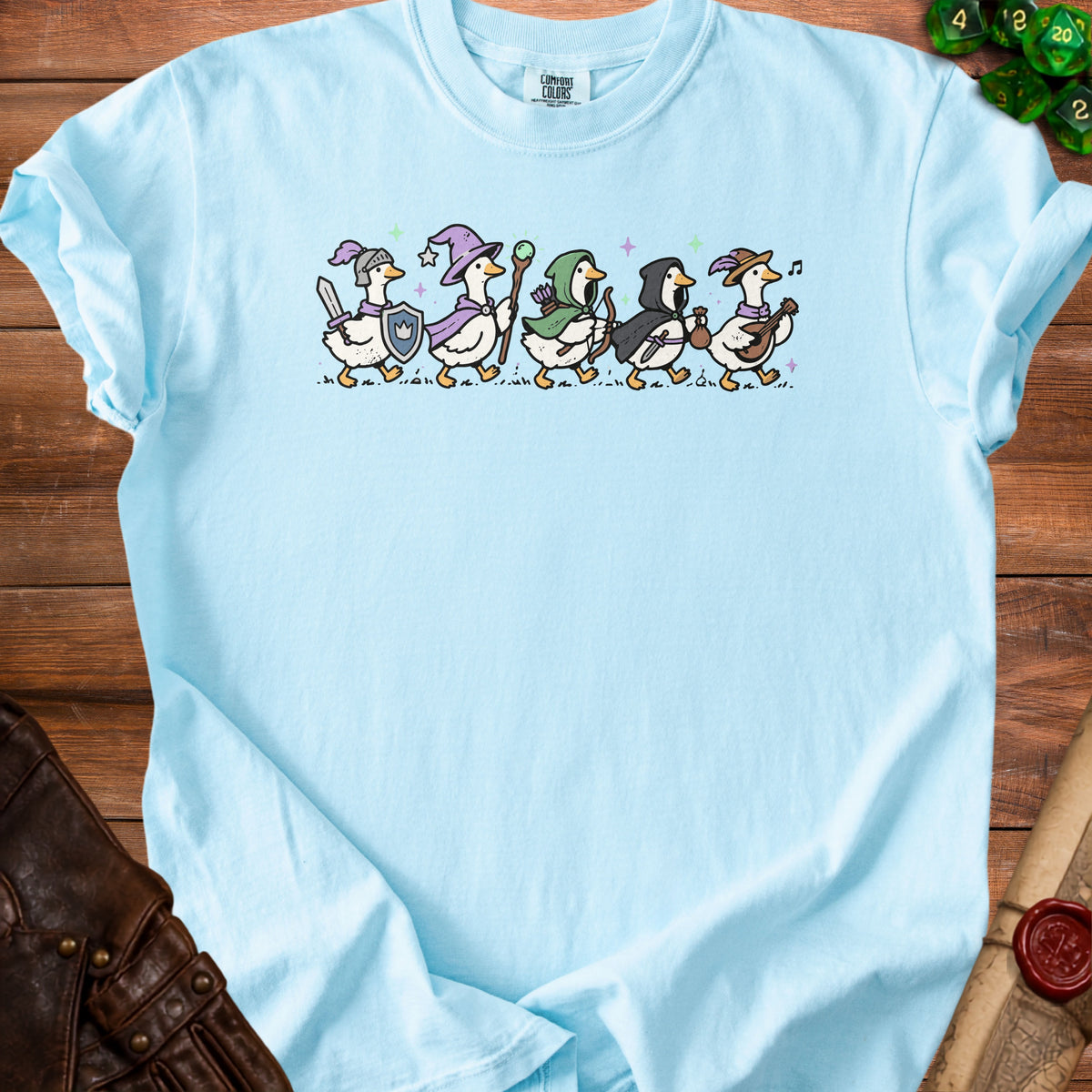 Light blue t-shirt with a row of fantasy-dressed geese characters.