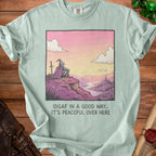 Light blue t-shirt with a drawing of a knight sitting on a cliff overlooking a castle and river.