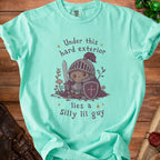 Light teal t-shirt with a knight illustration and text "Under this hard exterior lies a Silly lil guy".