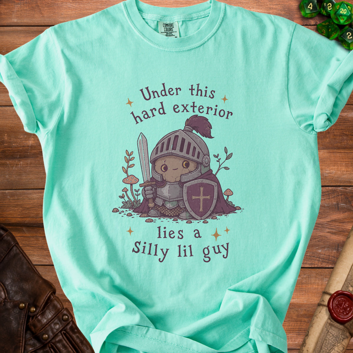 Light teal t-shirt with a knight illustration and text "Under this hard exterior lies a Silly lil guy".