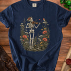 A dark blue t-shirt featuring a skeleton playing a violin surrounded by wildflowers and a bird.
