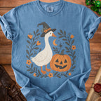 Blue t-shirt with graphic of goose in witch hat, pumpkin, and floral border.