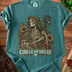 Skeleton in cloak with staff surrounded by plants and mushrooms, text "CIRCLE OF DECAY".