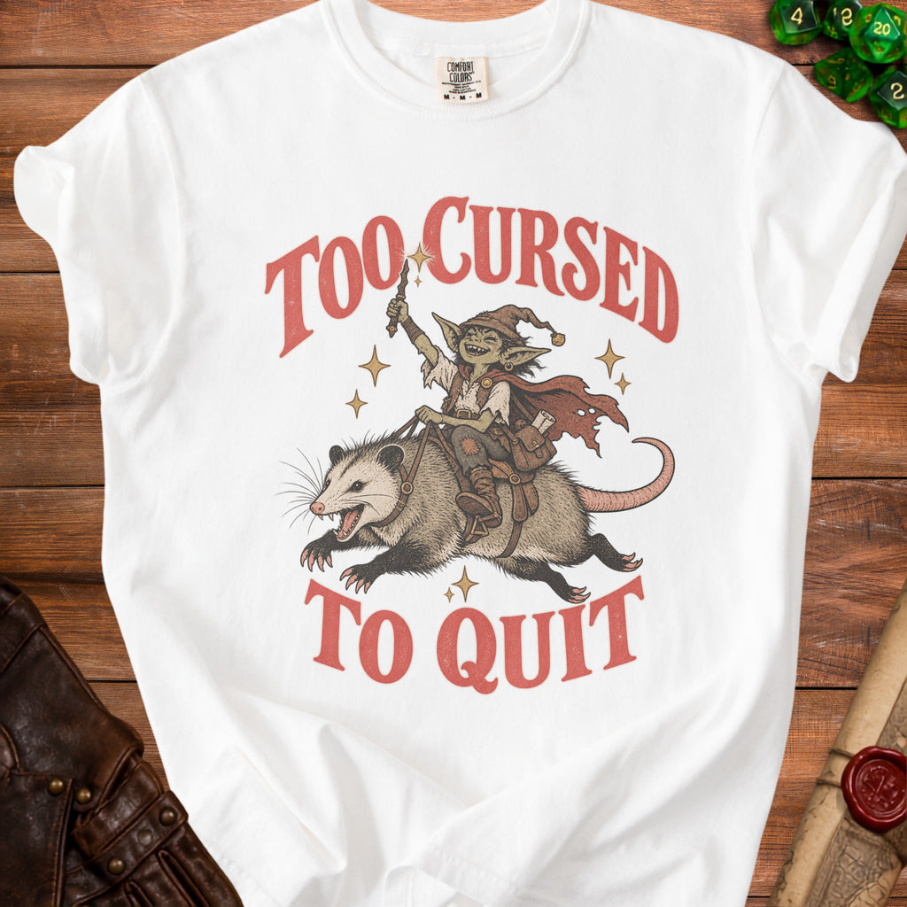 White t-shirt with graphic of goblin riding opossum, text "Too Cursed To Quit".
