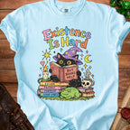 Light blue t-shirt with black cat reading "But Books Help" on stack of books.