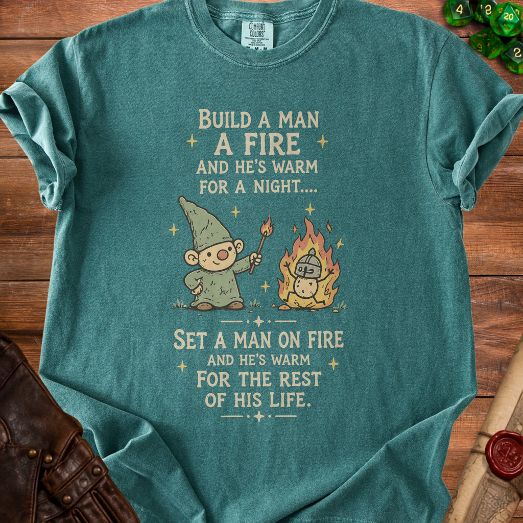 Teal t-shirt with cartoon gnome and fire, reading "Build a man a fire..."