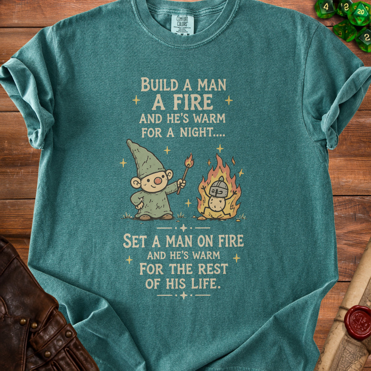Teal t-shirt with cartoon gnome and fire, reading "Build a man a fire..."