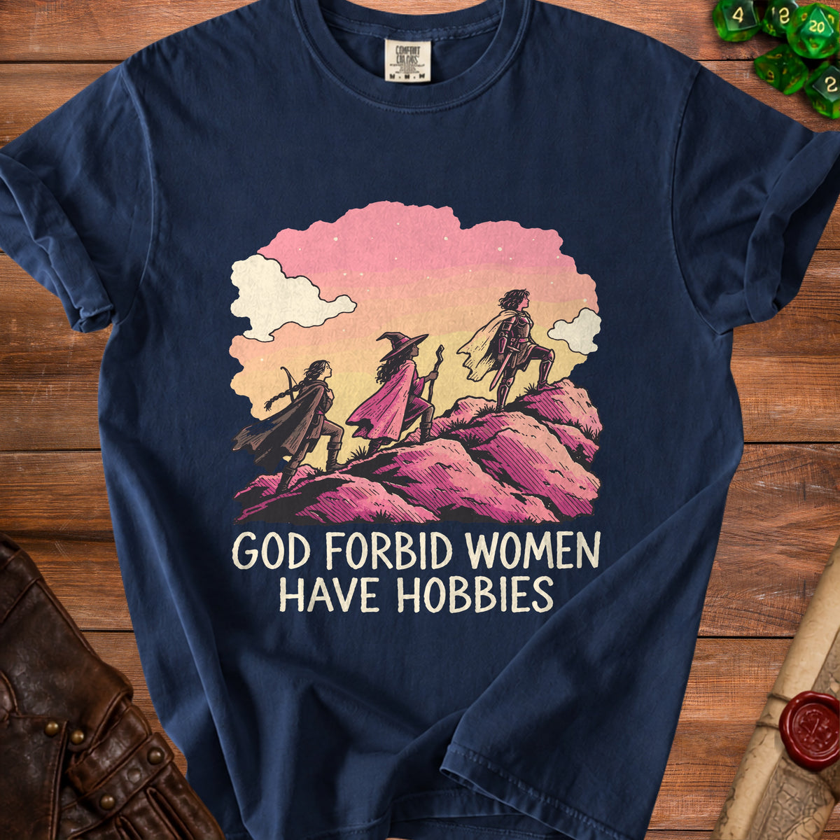Dark blue t-shirt featuring three women adventuring on pink hills with the text GOD FORBID WOMEN HAVE HOBBIES.