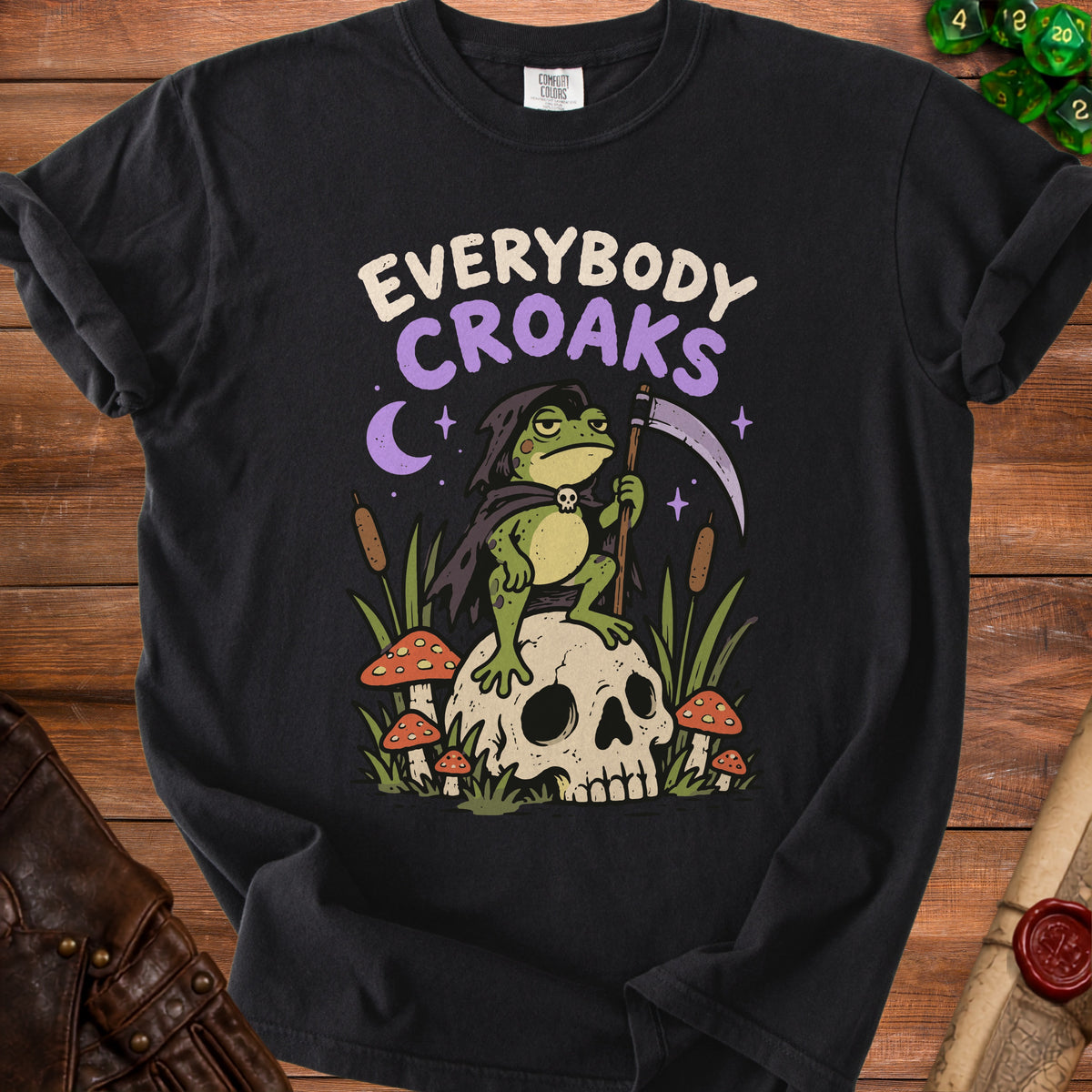 A grim reaper frog sits on a skull with mushrooms and reeds, with "EVERYBODY CROAKS" text.