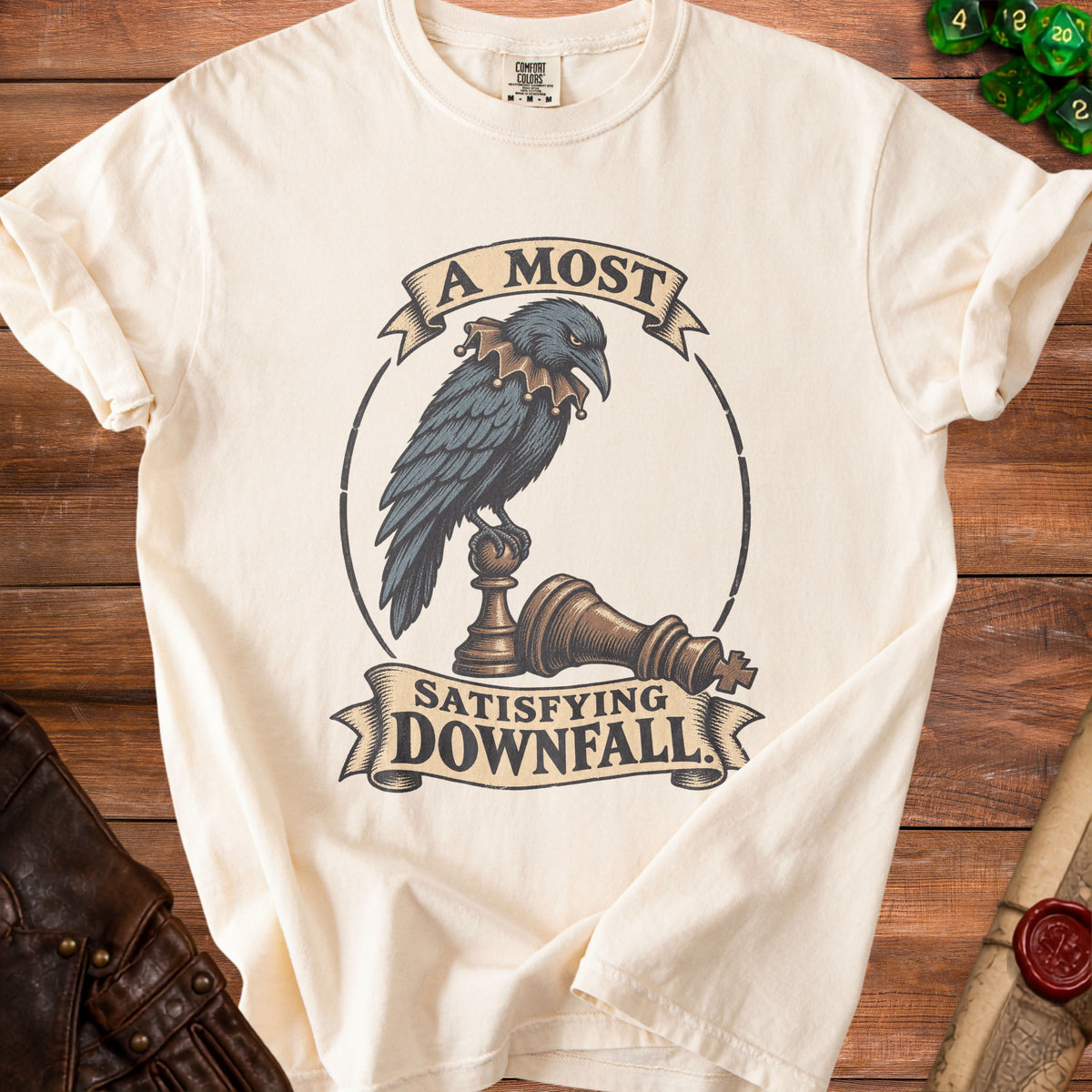A cream-colored t-shirt with a graphic of a crow perched on a fallen chess piece, accompanied by text.