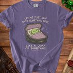 Purple t-shirt graphic of a green creature sleeping in an open coffin with text.
