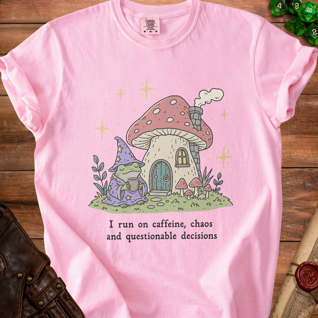 Pink t-shirt with illustration of wizard frog and mushroom house, text "I run on caffeine, chaos and questionable decisions".