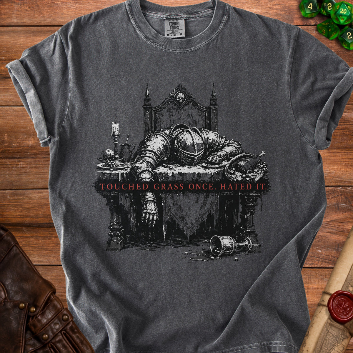 Dark gray t-shirt graphic of knight slumped over table with text "TOUCHED GRASS ONCE. HATED IT."