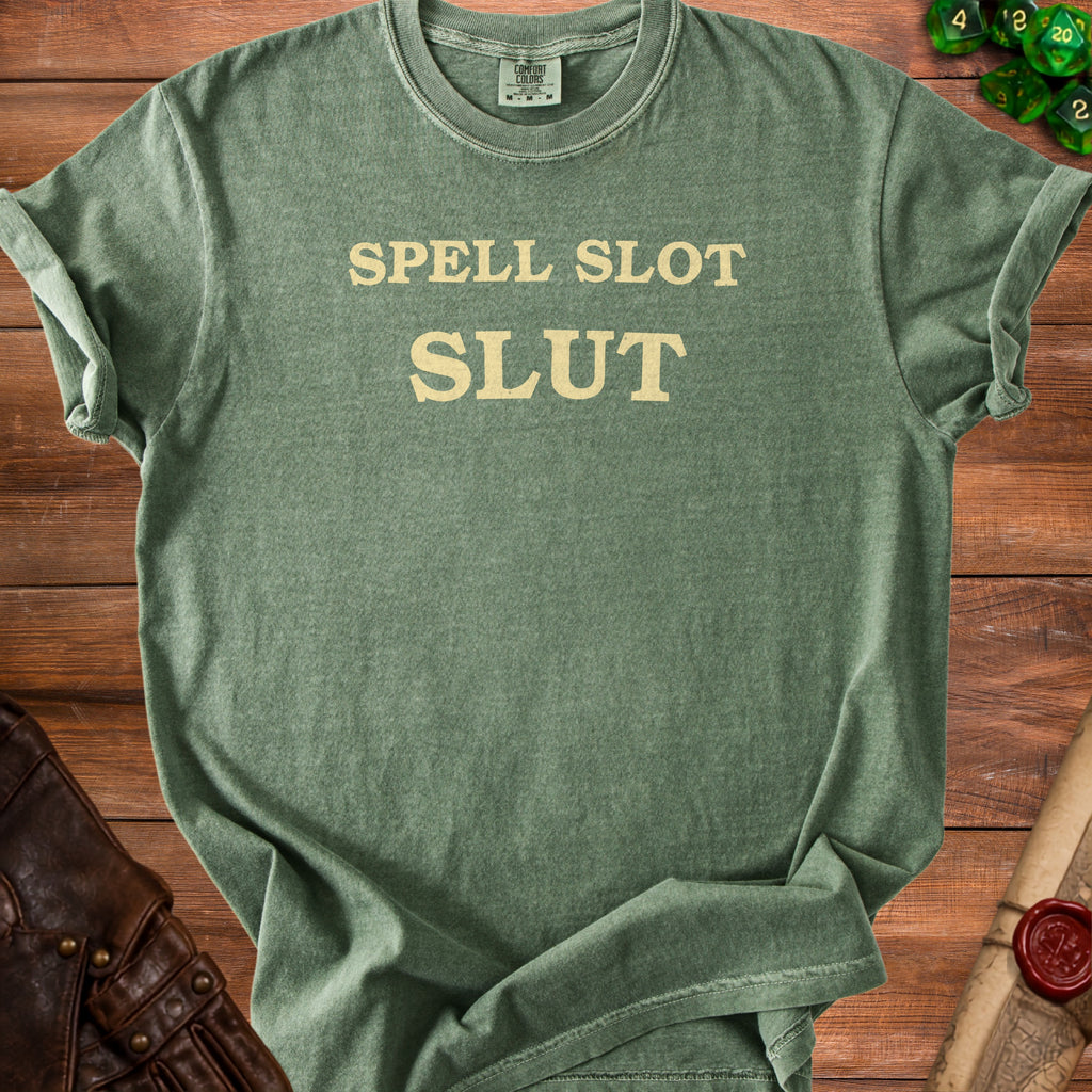 Green t-shirt with "SPELL SLOT SLUT" printed in beige text.
